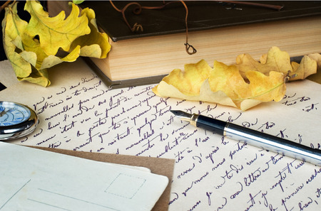 still life with an old letter, pen, book and yellow leaves