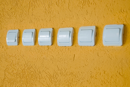 row of white electric switches on the orange wallの写真素材