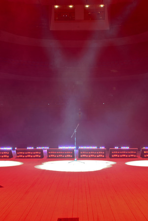 Illuminated empty theater stage with smoke and microphone