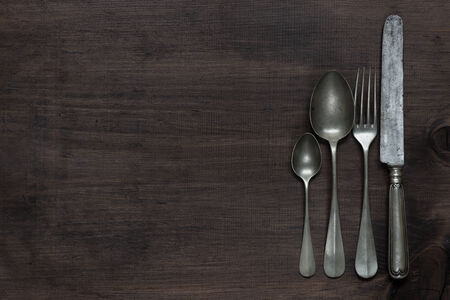 Row of vintage knife, fork and spoons on old wooden boardsの写真素材