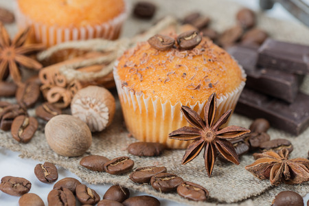 Cupcakes with chocolate shavings surrounded by coffee beans and a variety of spicesの写真素材