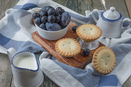 Three small enclosed cake with plums and a creamer and sugar bowl in vintage styleの写真素材