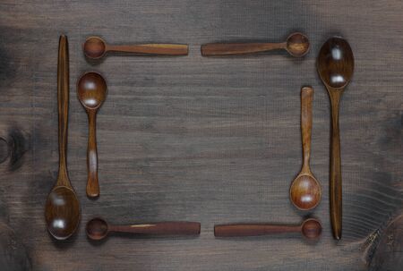 Wooden spoons lie on a dark wooden background in the form of a frameの写真素材