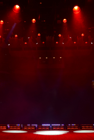 Illuminated empty concert stage with smoke and light beams, vertical image