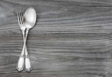 Crossed vintage forks and spoons on old wooden boards; with space for textの写真素材