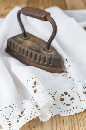 Old clothing iron and antique white lace doily on a wooden backgroundの写真素材