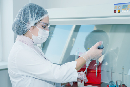 Woman scientist in a white protective clothing conducts research in a labの写真素材