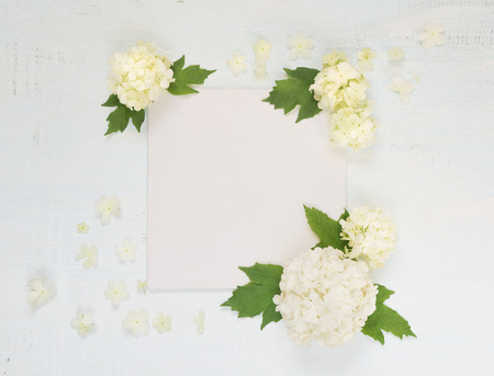 Scrapbooking page of wedding or family photo album, frame with fresh white flowers and green leaves on light wooden background; top view, flat lay, overhead viewの写真素材