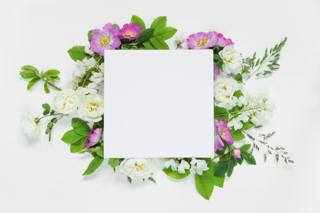 Scrapbook page of wedding or family photo album, frame with wild rose, white flowers and green leaves on light wooden background; top view, flat lay, overhead viewの写真素材