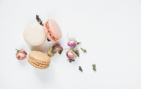 Traditional French multicoloured macaroons,d dried rose buds and green tea on white background; top view, flat layの写真素材