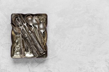 Various silverware in a metal tray on the background of gray concrete surface; with copy-spaceの写真素材