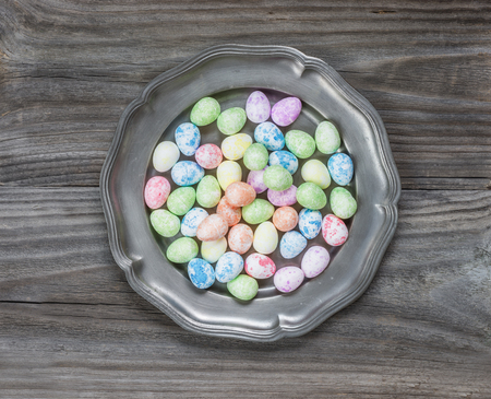 Many multi-colored Easter eggs in an ancient tin plate on an old wooden table