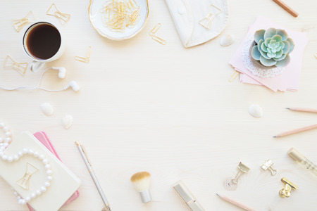 Female home office desk table in pastel tones. Workspace with notebooks, cup of coffe and decorations on light wooden background with copy-space. Flat lay, top viewの写真素材
