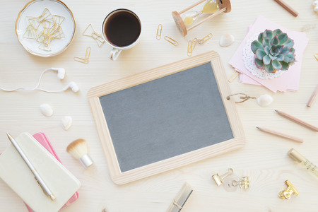 Female home office desk table in pastel tones. Workspace with blank slate, notebooks, cup of coffe and decorations on light wooden background with copy-space. Flat lay, top viewの写真素材