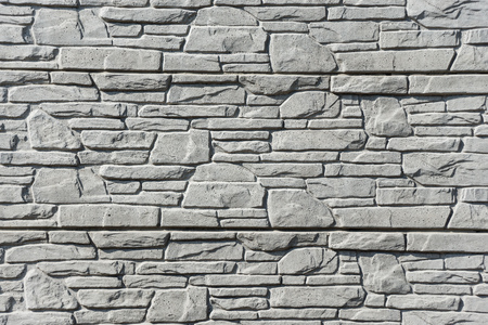 Texture of an old rough gray stone wall close-up