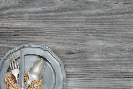 Vintage spoon, knife and fork are on pewter plate on the old gray wooden background, with copy-spaceの写真素材
