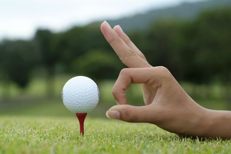 Hand and golf ball on teeの写真素材