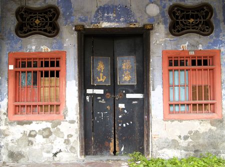 Old, worn entrance door and windows of Chinese townhouse in Georgetown, Penang, Malaysia.の写真素材
