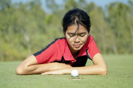 Young, female golf player and a golf ball that almost made it.の写真素材