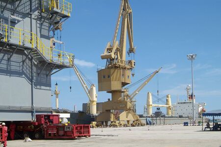Scene from industrial port with freight ship, crane and big steel structure being moved by...