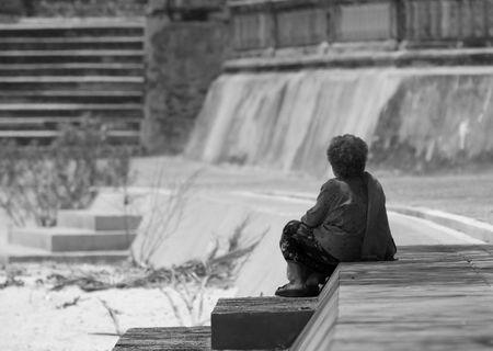 Old woman sitting at the top of the stairs, waiting. Black and white photo with shallow depth of field. Only the woman in focus.の写真素材