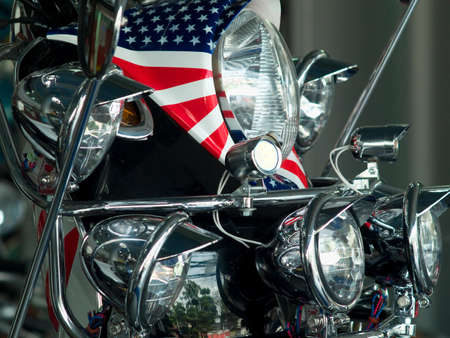 Detail of scooter with the pattern of the American flag wrapped around the headlight and lots of extra lights.の写真素材