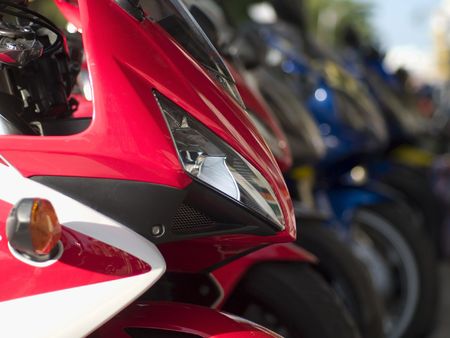 Front detail of heavy motorbike. Long row of blurred motorbikes in the background.の写真素材
