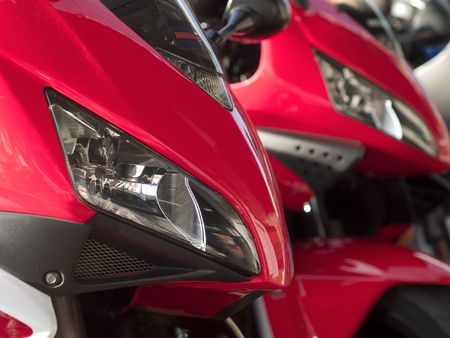 Details of two red motorbikes, one sharp in the foreground and one blurred in the backgroundの写真素材