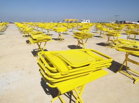 Yellow tables with folded chairs on top, disappearing into the horizonの写真素材
