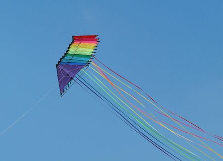 A string of colourful stunt kites with long tails on a blue sky backgroundの写真素材