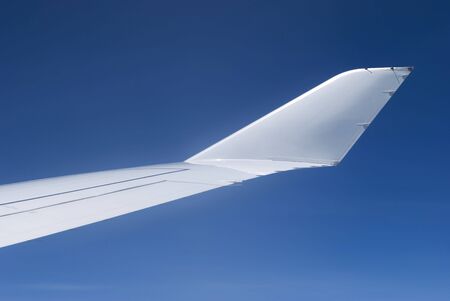 Wing-tip with winglet of passenger airplane flying on a blue sky background.の写真素材