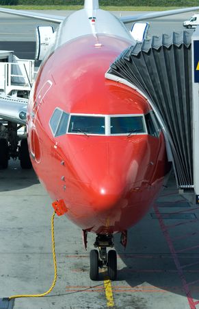 Red and white passenger airplane at the gate of an airport