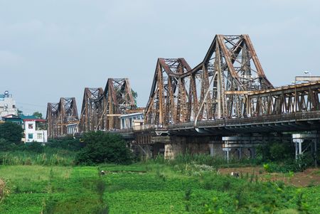 The Long Bien railway bridge crossing the Red River in Hanoi, seen from the island in the river. The bridge was constructed by Gustave Eiffel in 1903. It was heavily bombed during the Vietnam war, but rebuild on a continous basis.の写真素材