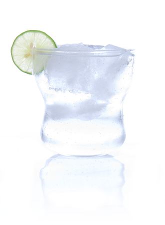 Glass of soda water with ice cubes and a slice of lime. High-key photo, isolated on white with reflection in the foreground.の写真素材