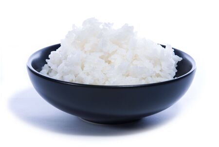 Black bowl with white rice isolated on white.の写真素材