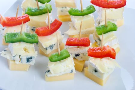 Cheese snacks with three kinds of cheese and pieces of capsicum, on a white plate.の写真素材