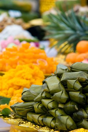 Thai sweets wrapped in pandanus leaves at a Buddhist temple ceremony in Thailand. Shallow depth of field with the nearest sweets in focus.の写真素材