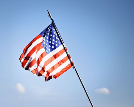 Small, American flag on a blue sky backgroundの写真素材
