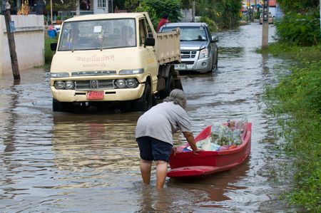 AYUTTAYA - OCTOBER 20: Woman using a small boat to transport food down a narrow road during unusually heavy monsoon flooding on October 20, 2010 in Ayuttaya, Thailand. のeditorial素材