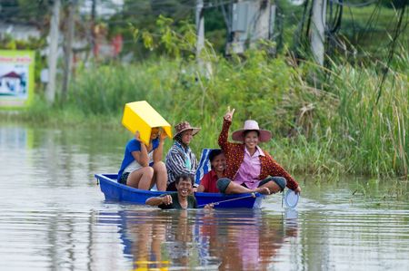 NAKHON RATCHASIMA - OCTOBER 24: Villagers floating through deep water on a small plastic dinghy during the monsoon flooding of October 24, 2010 in Nakhon Ratchasima, Thailand.のeditorial素材