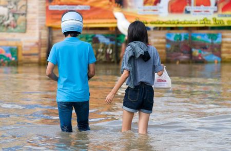 NAKHON RATCHASIMA - OCTOBER 24: Young couple wading through the streets of the city during the worst monsoon flood in 50 years on October 24, 2010 in Nakhon Ratchasima, Thailand.のeditorial素材