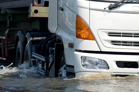 Front detail of white truck driving on a flooded road.のeditorial素材