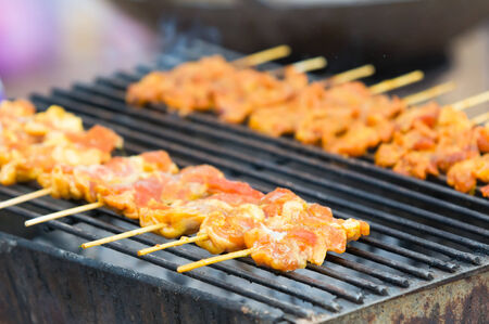 Pieces of pork on wooden sticks on a barbecue in Thailand  Very shallow depth of field with the nearest pieces of pork in focus の写真素材