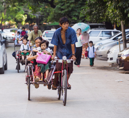 YANGON, MYANMAR - NOVEMBER 13, 2014: Children being taken to school on cyclos. The cyclo is an important mode of transportation in the Myanmar capital, where motorbikes are forbidden.のeditorial素材