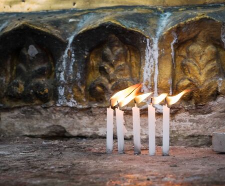 Five candles burning at dawn in front of a golden stupa at the Shwedagon Pagoda in Yangon, Myanmar. Shallow depth of field with the candles in focus.の写真素材