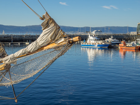 The Brattor Quay in downtown Trondheim, Norway, with the bowsprit of a sailing ship in the foreground and a pilot boat and other utility vessels out if focus in the background.のeditorial素材