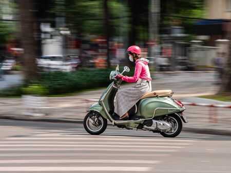 Ho Chi Minh City, Vietnam - January 11, 2016: Young woman driving her elegant Vespa scooter in...