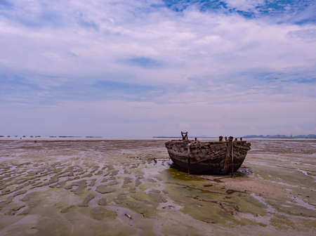 Old wooden barge stranded at low tide in Naklua, Chonburi Province, Thailand.