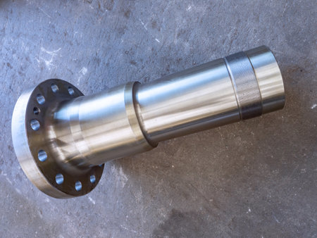 Stainless steel, heavy duty industrial stub shaft on a dirty concrete floor.