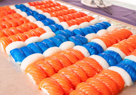 Nigiri sushi pieces, 140 of them, made from salmon, white fish and blue coloured white fish arranged to look like a Norwegian flag. Shallow depth of field with some of the nearest pieces in focus.の写真素材